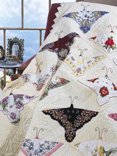 Vintage hankies placed to look like butterflies on a white quilt with the feelers embroidered in black. #vintage #hankies #quilt